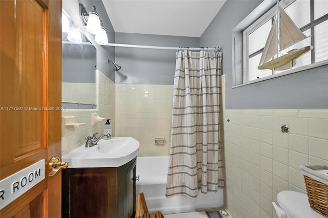 full bath with shower / bathtub combination with curtain, vanity, toilet, wainscoting, and tile walls