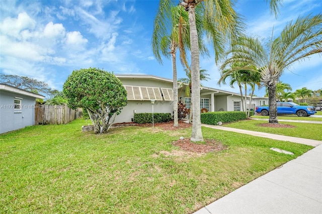view of front of house with a front yard, fence, and stucco siding