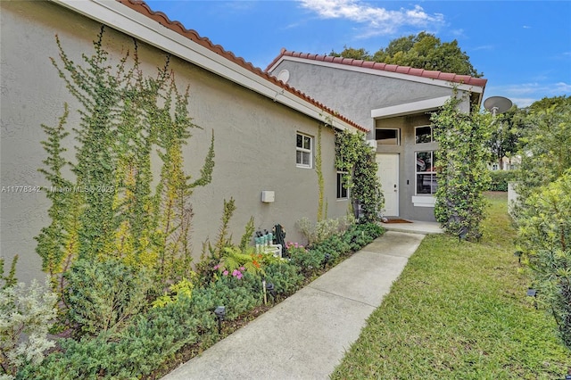 property entrance featuring a lawn, stucco siding, and a tile roof