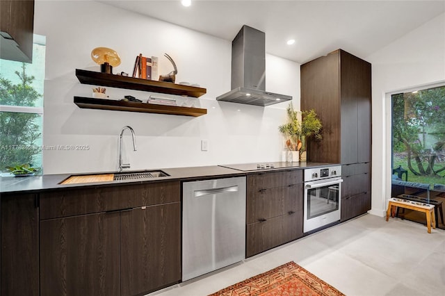 kitchen featuring dark brown cabinetry, open shelves, a sink, stainless steel appliances, and wall chimney exhaust hood