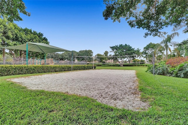 view of property's community with a lawn, fence, and volleyball court
