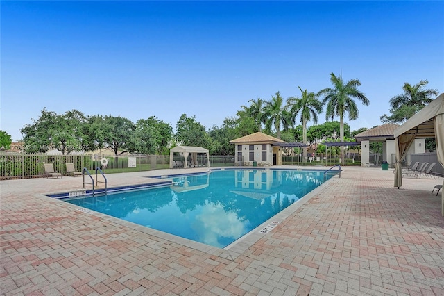 community pool featuring fence, a gazebo, and a patio area