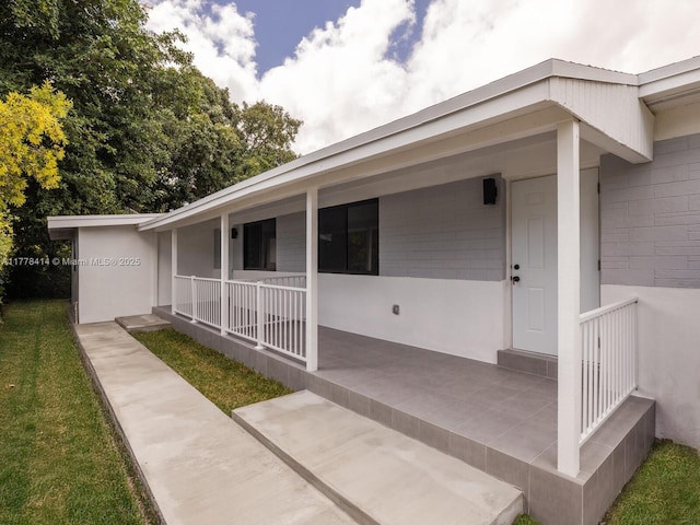 doorway to property featuring a porch and stucco siding