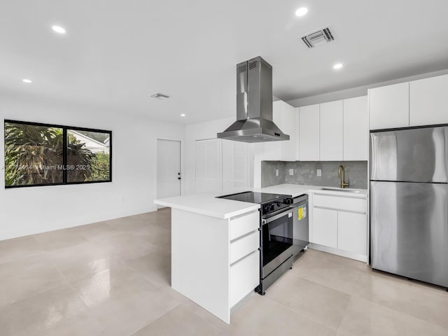 kitchen featuring wall chimney exhaust hood, visible vents, light countertops, a sink, and stainless steel appliances
