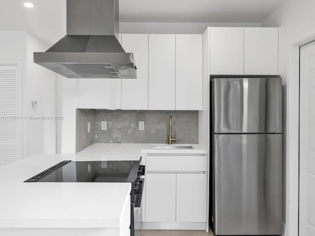 kitchen with freestanding refrigerator, wall chimney exhaust hood, decorative backsplash, black range with electric stovetop, and a sink