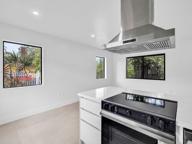 kitchen with wall chimney range hood, white cabinetry, recessed lighting, light countertops, and range with electric cooktop