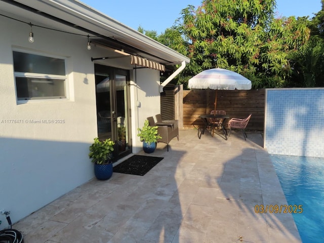 view of patio with outdoor dining area, fence, and french doors