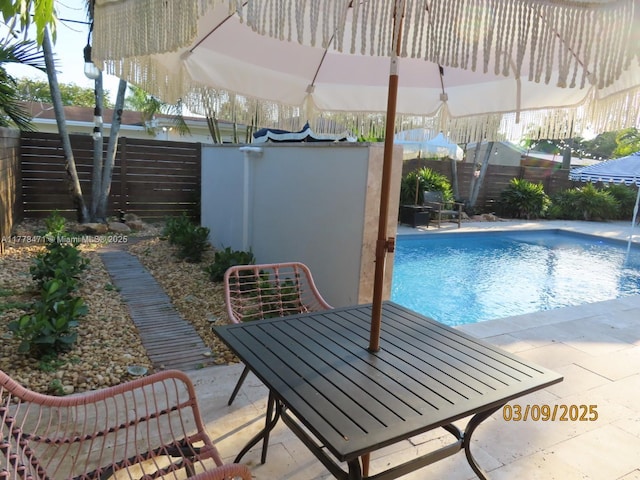 view of pool with a patio, a fenced in pool, a fenced backyard, and outdoor dining space