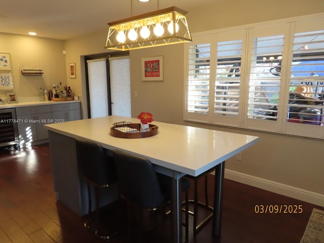 dining area with a bar, dark wood-style floors, baseboards, and beverage cooler