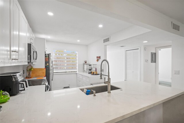 kitchen featuring recessed lighting, stainless steel appliances, a sink, visible vents, and white cabinets
