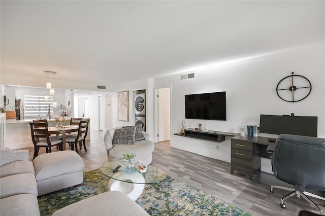living area featuring wood finished floors, stacked washing maching and dryer, and visible vents
