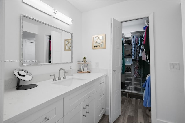 bathroom with a spacious closet, wood finished floors, and vanity