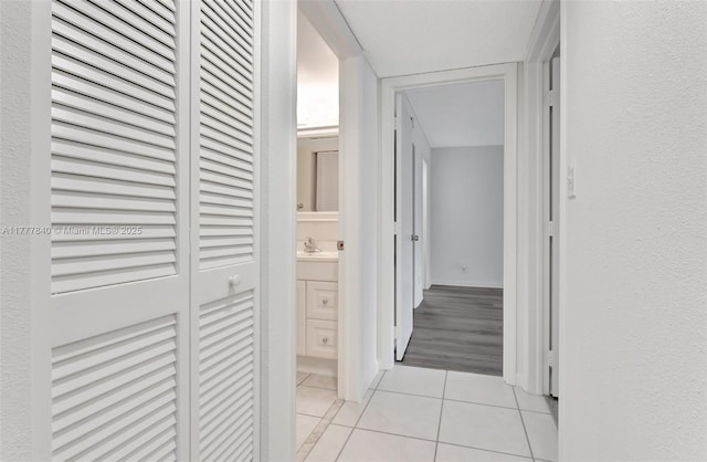 hallway with light tile patterned flooring and a sink