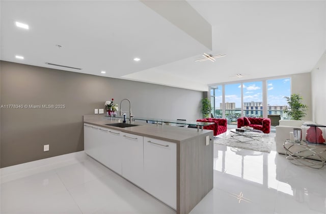 kitchen with white cabinets, modern cabinets, a sink, light countertops, and a peninsula