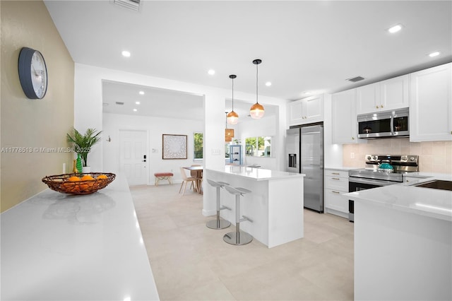 kitchen with tasteful backsplash, hanging light fixtures, white cabinets, recessed lighting, and stainless steel appliances