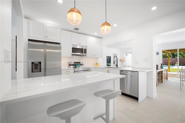 kitchen with stainless steel appliances, a peninsula, a sink, and backsplash