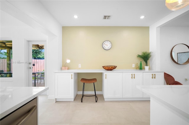 kitchen with built in desk, baseboards, recessed lighting, white cabinets, and visible vents