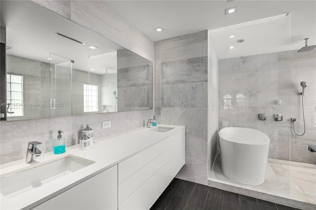 3106 NE 210th Ter, Aventura, FL 33180 - bathroom featuring tile walls, a tile shower, double vanity, and a soaking tub