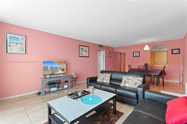 living room featuring visible vents, baseboards, light tile patterned flooring, and a textured ceiling