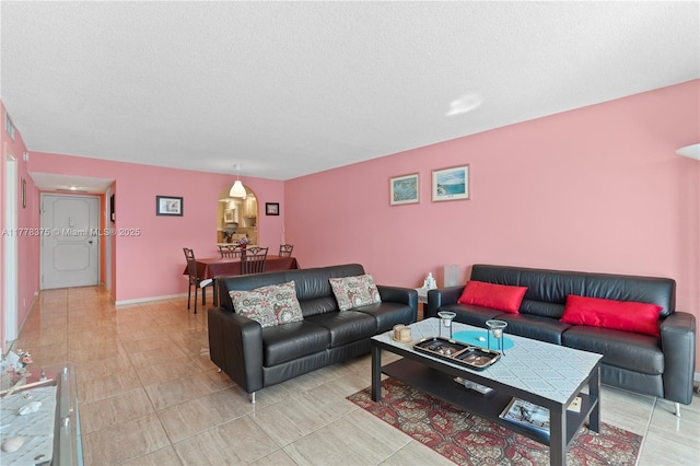 living area featuring light tile patterned floors, baseboards, and a textured ceiling