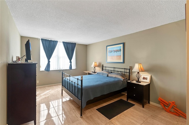 bedroom featuring light tile patterned floors, baseboards, and a textured ceiling
