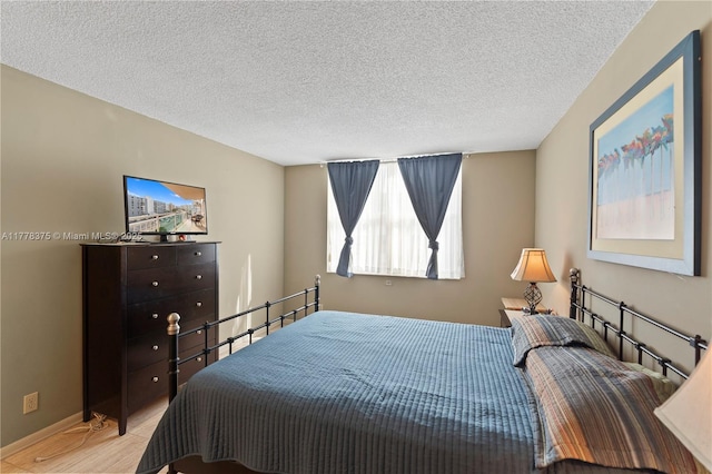 bedroom featuring a textured ceiling, wood finished floors, and baseboards