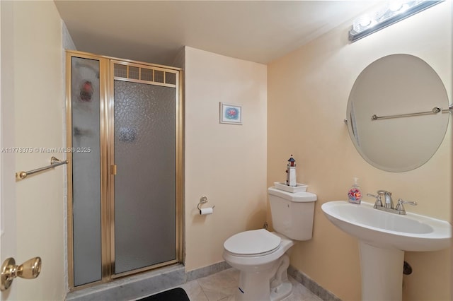 bathroom featuring baseboards, tile patterned floors, toilet, a shower stall, and a sink
