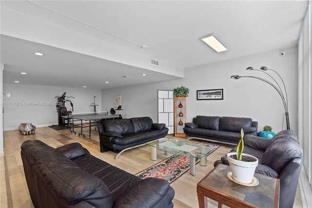 living room with recessed lighting, light wood finished floors, visible vents, and baseboards