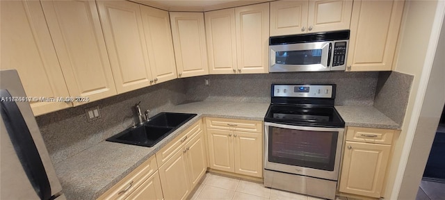 kitchen with a sink, light tile patterned floors, light countertops, and stainless steel appliances