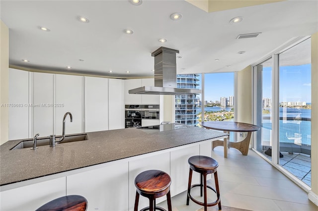2600 E Island Blvd Unit 1704, Aventura, FL 33160 - kitchen featuring black electric stovetop, island range hood, expansive windows, white cabinets, and recessed lighting
