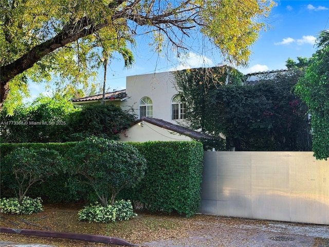 view of side of property with fence and stucco siding