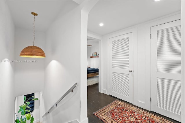 corridor with an upstairs landing, recessed lighting, and dark wood-style floors
