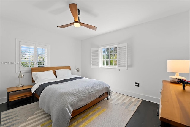 bedroom featuring a ceiling fan, wood finished floors, baseboards, and multiple windows