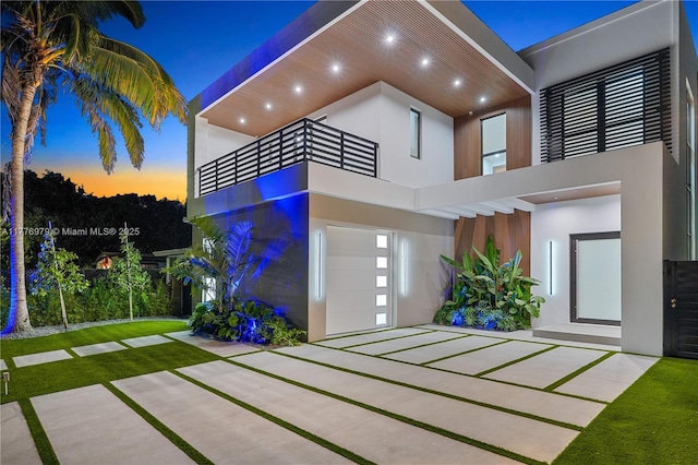 view of front of house featuring a garage, stucco siding, and a balcony