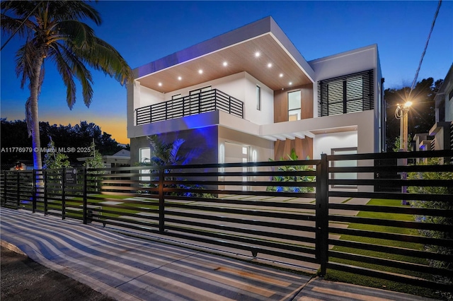 exterior space featuring an attached garage, a fenced front yard, stucco siding, and a balcony