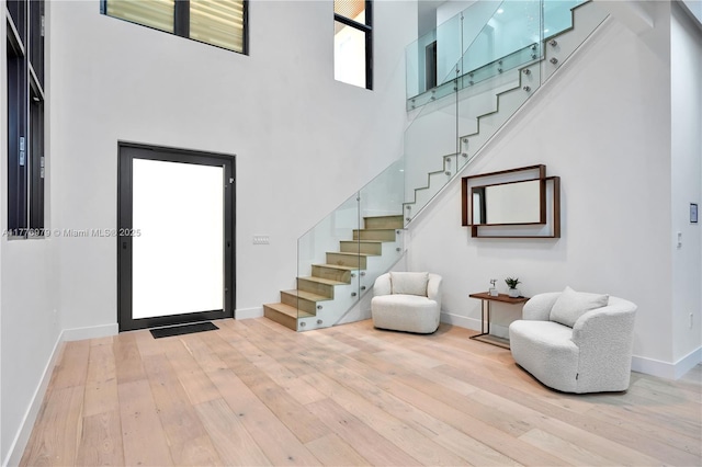 foyer entrance featuring baseboards, stairway, a high ceiling, and hardwood / wood-style flooring