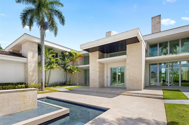 back of house featuring french doors, a patio, a chimney, and stucco siding