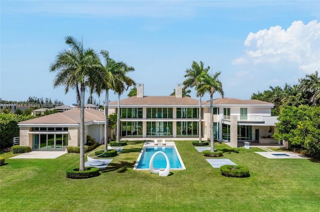 back of property with a patio, a yard, stucco siding, and a chimney