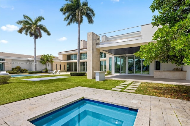 rear view of house featuring a patio, a yard, stucco siding, and an outdoor kitchen
