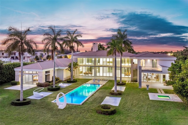back of property with a yard, stucco siding, a patio, a balcony, and an outdoor pool