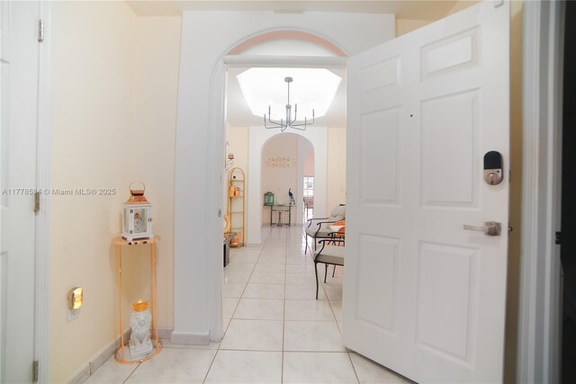 14426 NW 88th Ave, Miami Lakes, FL 33018 - hall with arched walkways, light tile patterned floors, a chandelier, and baseboards