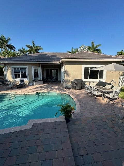 2269 Quail Roost Dr, Weston, FL 33327 - back of property with a patio area, an outdoor pool, stucco siding, and outdoor dining space