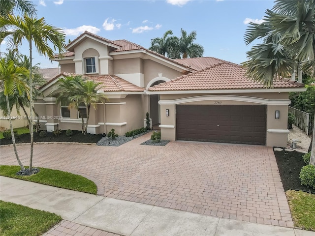 2269 Quail Roost Dr, Weston, FL 33327 - mediterranean / spanish house featuring a garage, stucco siding, decorative driveway, and a tiled roof