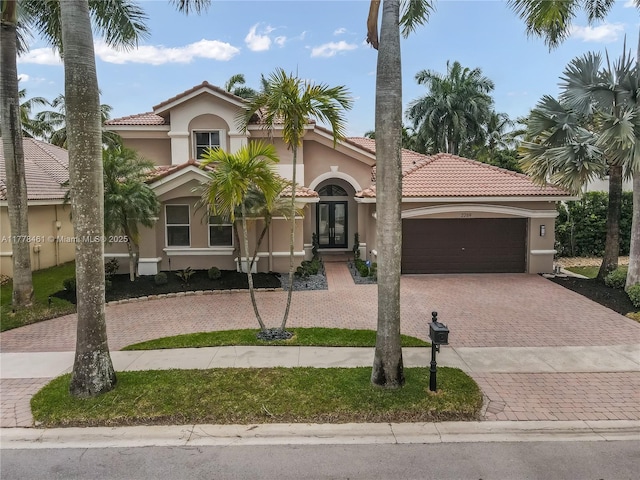 2269 Quail Roost Dr, Weston, FL 33327 - mediterranean / spanish-style house featuring french doors, decorative driveway, a tiled roof, and stucco siding
