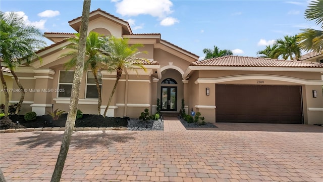 2269 Quail Roost Dr, Weston, FL 33327 - mediterranean / spanish-style home with stucco siding, french doors, an attached garage, a tile roof, and decorative driveway