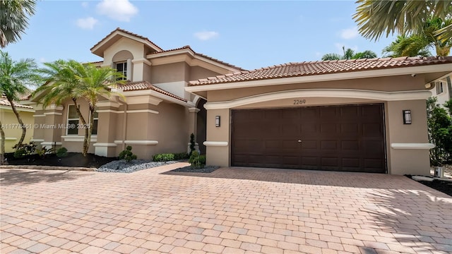 2269 Quail Roost Dr, Weston, FL 33327 - mediterranean / spanish-style home featuring stucco siding, decorative driveway, a garage, and a tiled roof