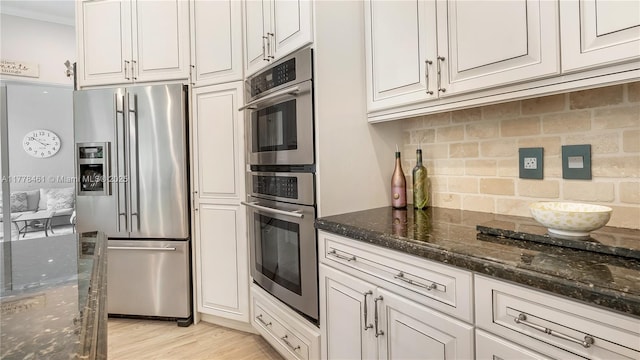 2269 Quail Roost Dr, Weston, FL 33327 - kitchen featuring stainless steel appliances, decorative backsplash, dark stone counters, white cabinetry, and light wood-style flooring