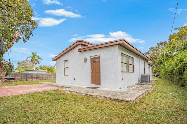 exterior space with central AC, stucco siding, a patio, a front yard, and fence