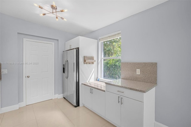 kitchen featuring tasteful backsplash, white cabinetry, stainless steel refrigerator with ice dispenser, a chandelier, and light tile patterned flooring