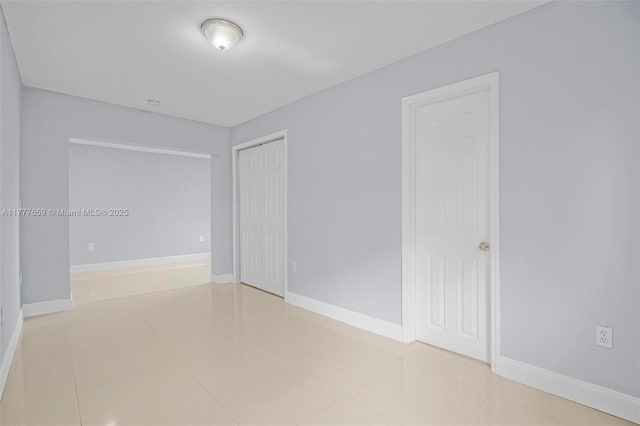 tiled spare room featuring baseboards